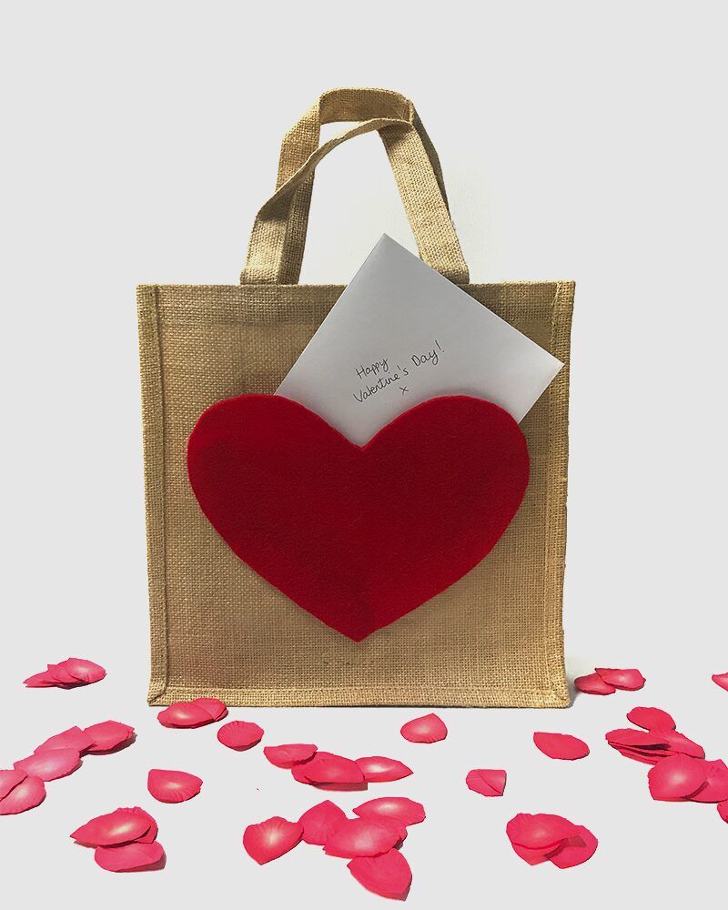 Hessian bag with red heart pocket, Valentine's Day card and red rose petals.